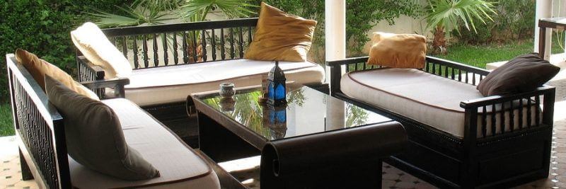 Patio furniture surrounded by flowers and palm trees.