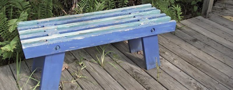 an old empty wooden peeling blue bench suffering from photobleaching