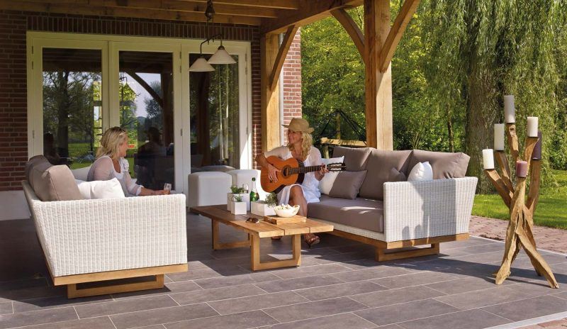 Two women sitting on a patio while one plays the guitar