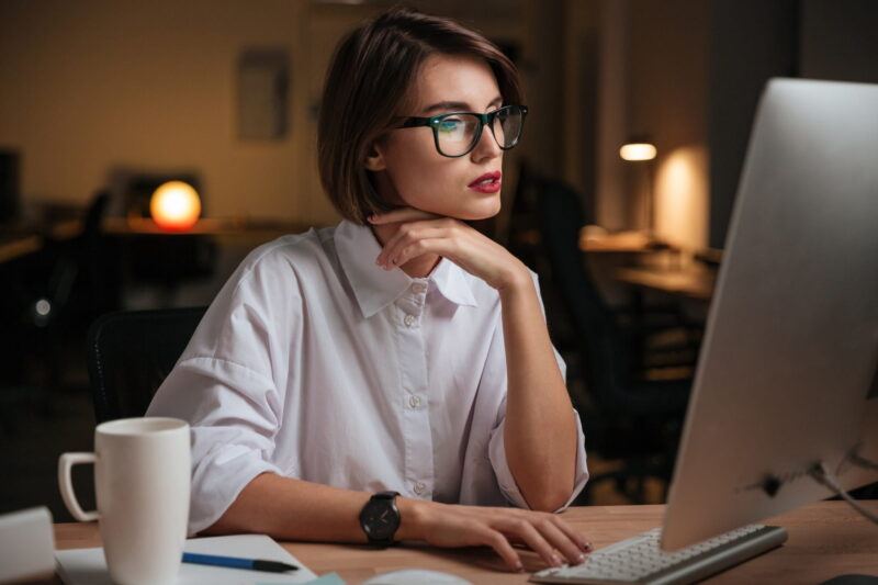 Woman with glasses looking at a desktop computer