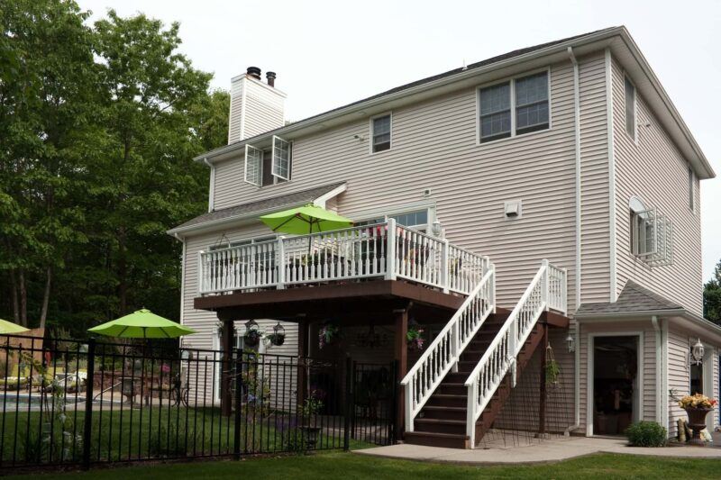 Backyard of a tan house with a deck